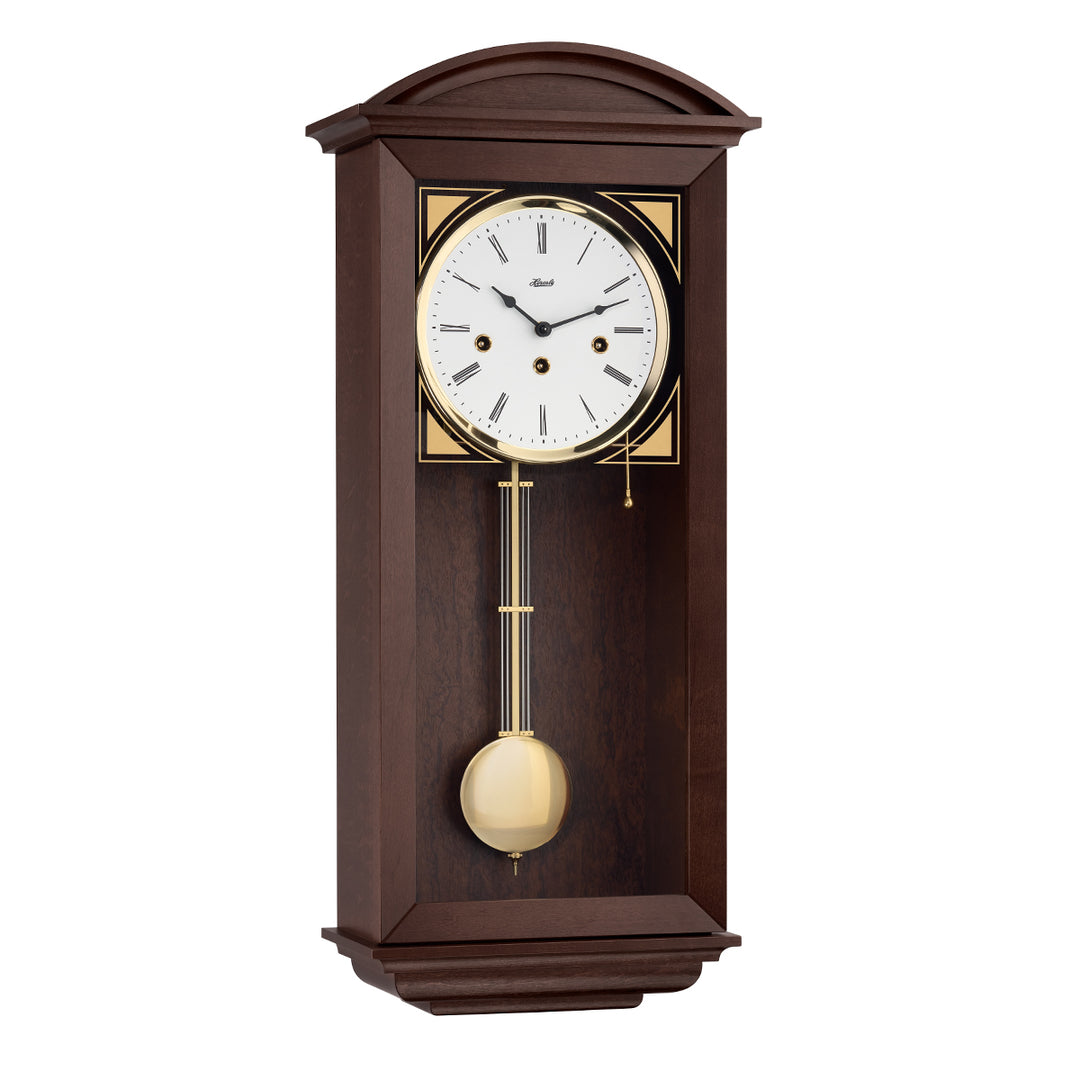 Retro style walnut wall clock with brass highlights and three holes in the face for winding the mechanical movement inside.