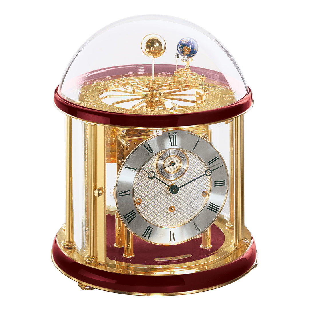 Red and brass Tellurium clock with glass dome and brass plated mechanical gears visible.