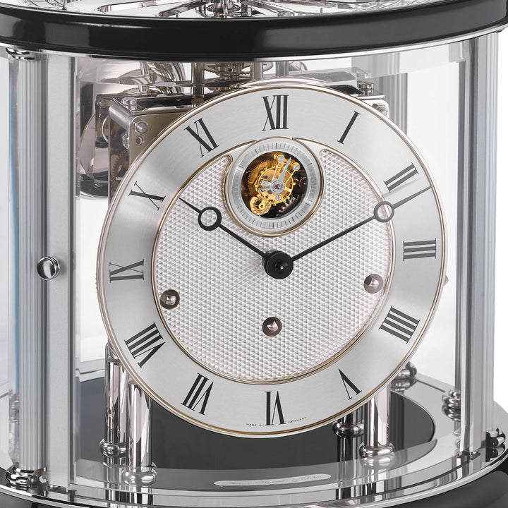 Up close of Tellurium clock face with silver color and roman numerals behind nickel framed glass.