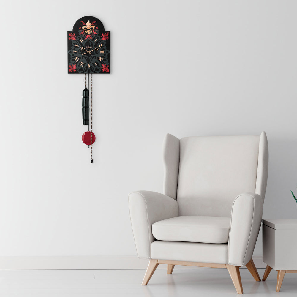 Black decorative wall clock with gold colored roman numerals hanging in white living room above white chair.