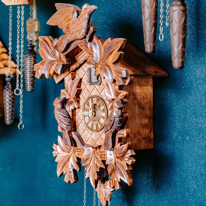 Cuckoo clock on blue wall surrounded by other clocks