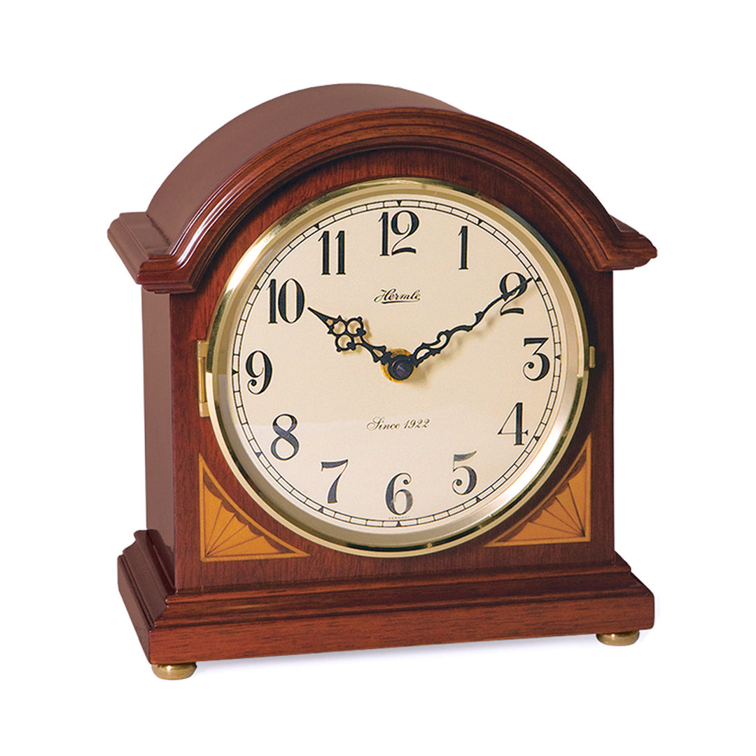 Cherry wood barrister mantel clock with brass highlights and ornate hands on white background.