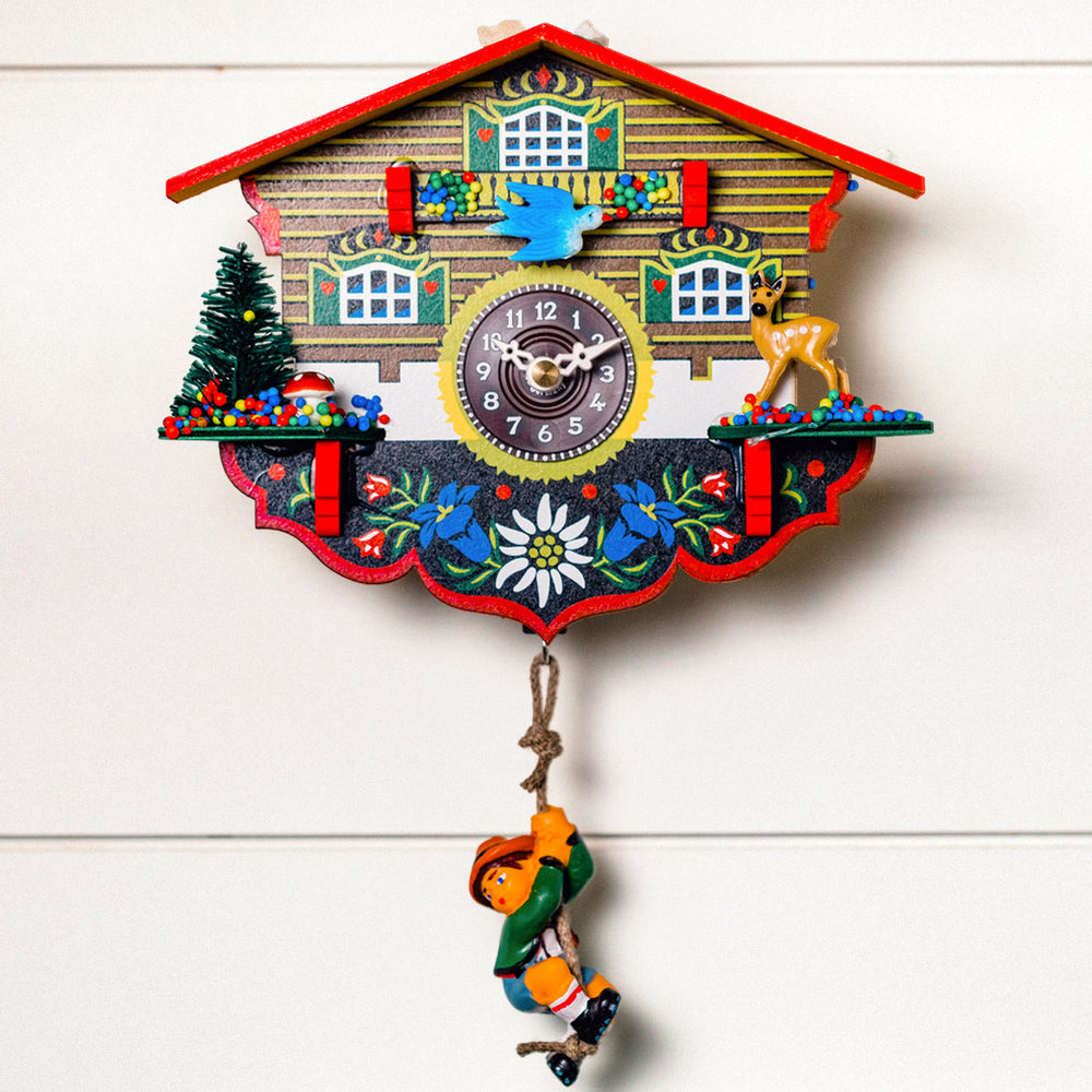 Decorative cuckoo clock with colorful design and blue bird hanging on white wall