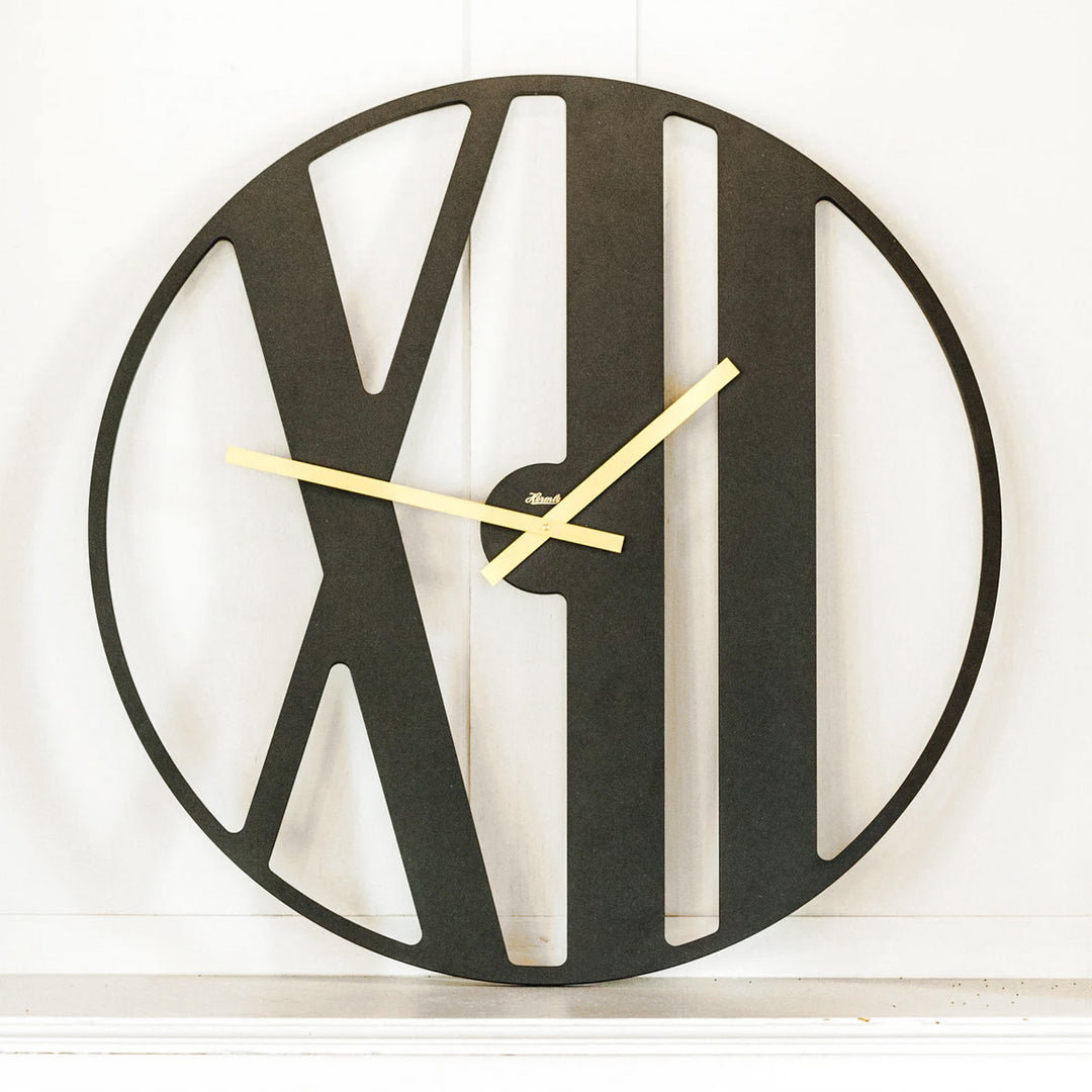 Black wall clock by Hermle with gold hands on a white background