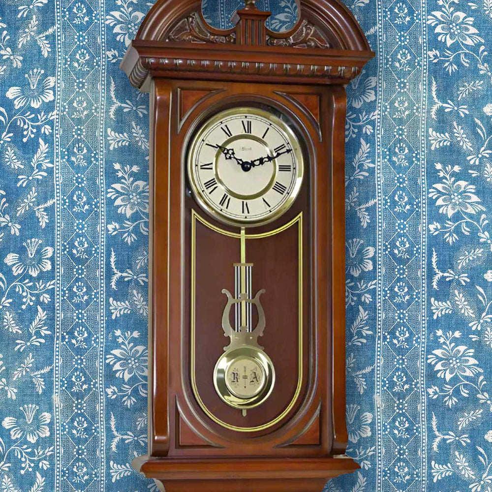 Wooden wall clock with decorative elements on a blue floral wallpaper background
