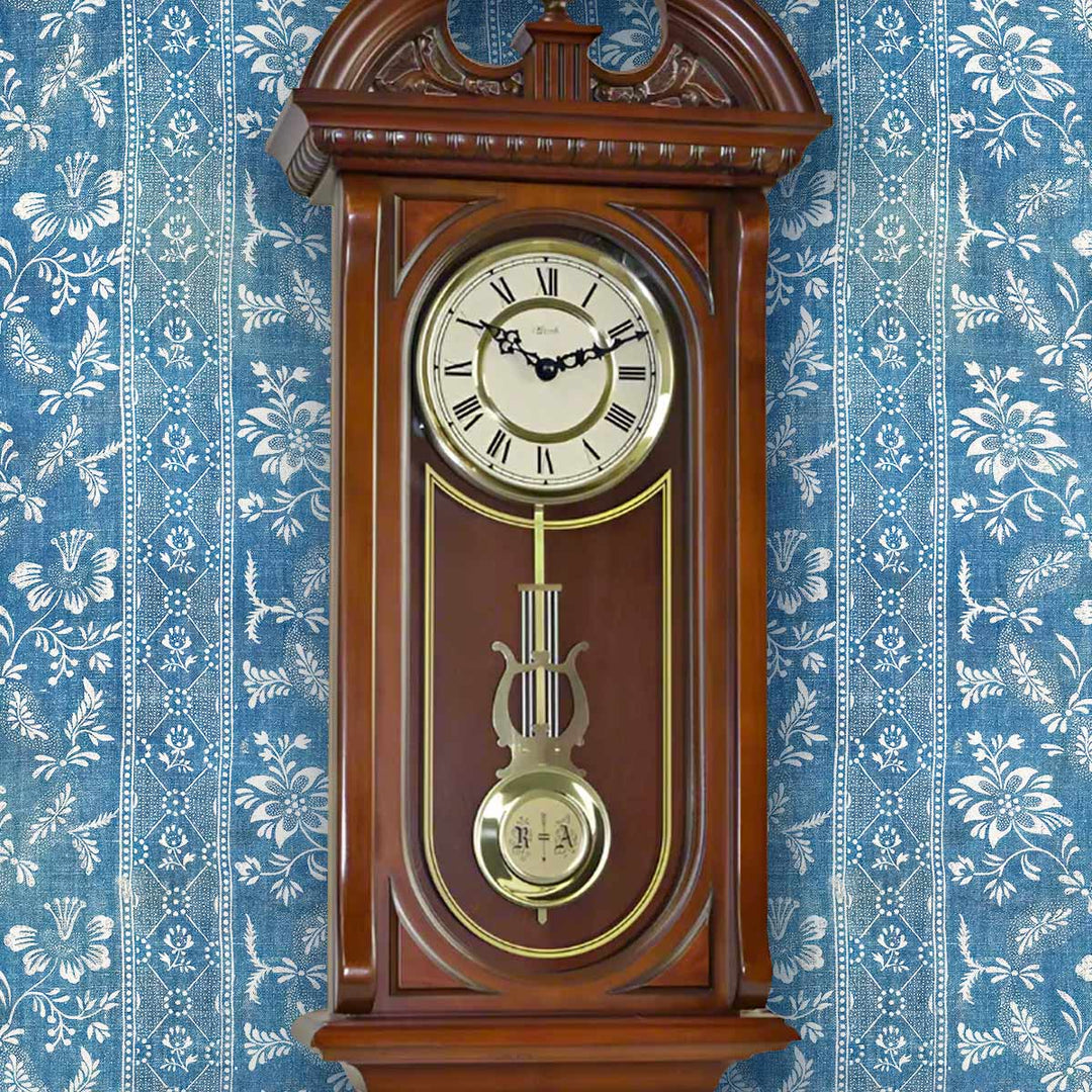 Wooden wall clock with decorative elements on a blue floral wallpaper background